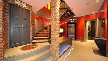 A modern hotel lobby with a staircase, a reception desk, and a shower area.