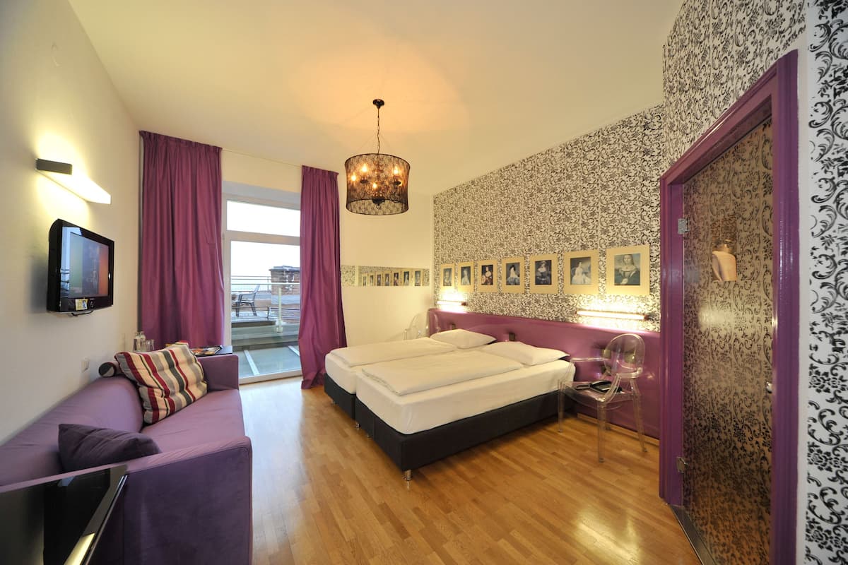 A modern bedroom with a bed, a sofa, a TV, and a view of the outside.