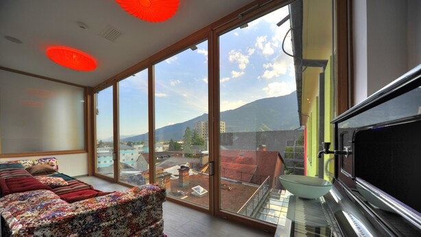 Una sala de estar moderna con un piano, ventanas amplias y vistas a la ciudad.