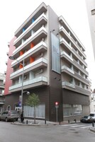 Un edificio de varios pisos con balcones, una señal visible y vista a la calle.