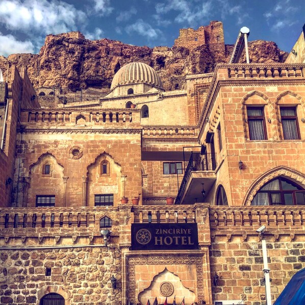 A historic building with a sign for ZINCIRIYE HOTEL, featuring traditional architecture with stone walls and arched windows. - Zinciriye Hotel - Special Class (Mardin)