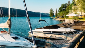 A marina with boats docked, a wooden dock, and a view of a lake with hills in the background.