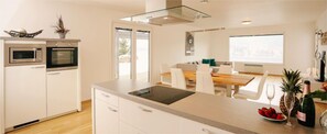 Een moderne keuken met een inbouwoven, magnetron en een groot kookeiland met spoelbak.