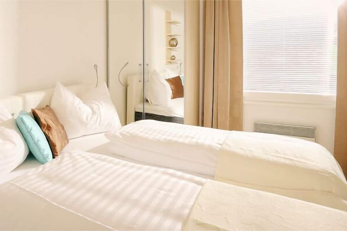 Una habitación de hotel con dos camas, un espejo y una estantería con objetos decorativos.