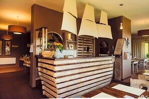 A reception desk with a wooden slat design, a vase with flowers, and pendant lighting.