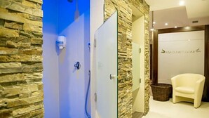 A spa room with a stone wall, a blue door, a white chair, and a reception area with a sign. - Na Skarpie (Chojnice)