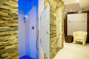 A spa room with a stone wall, a blue door, a white chair, and a reception area with a sign.
