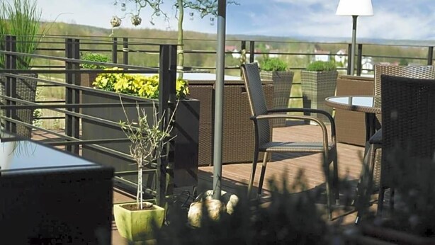 An outdoor patio with wicker furniture, potted plants, and a view of the landscape. - Na Skarpie (Chojnice)