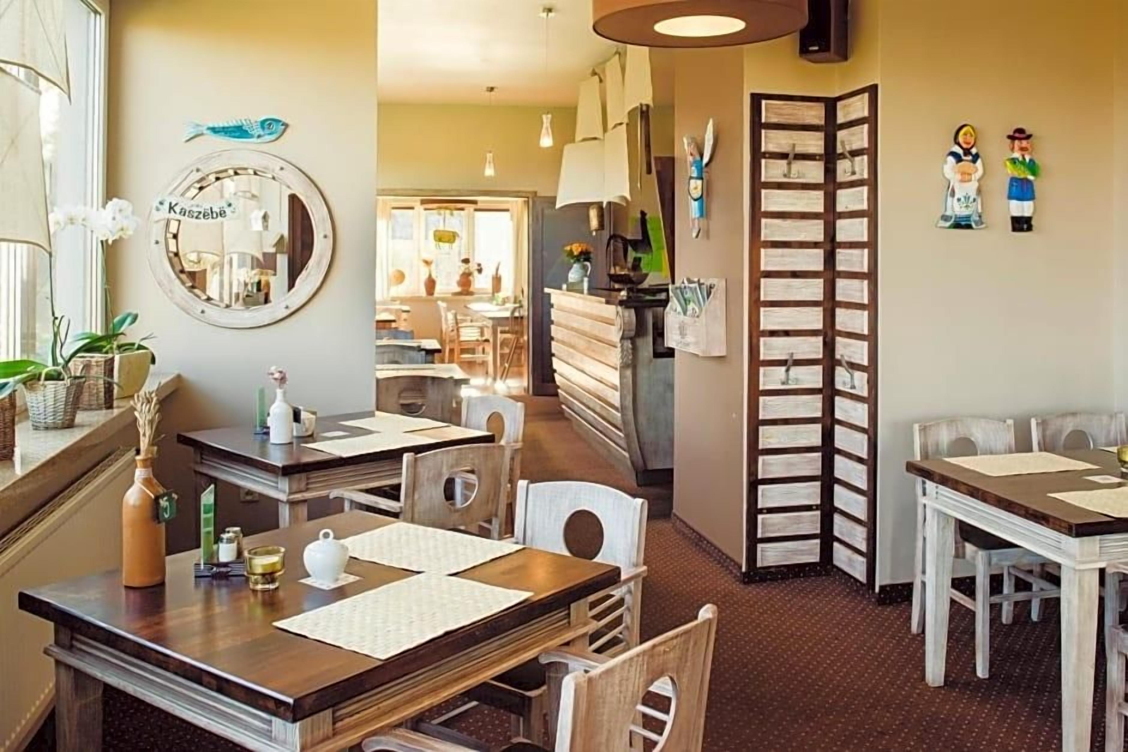 A dining area with wooden tables and chairs, a mirror, and a decorative fish sign.