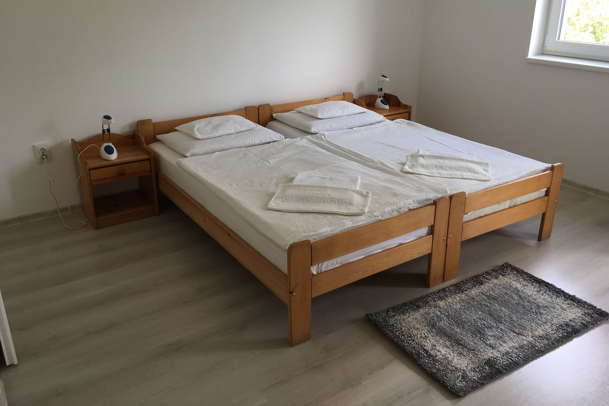 A bedroom with a wooden bed, two bedside tables, a nightstand, a window, and a rug.