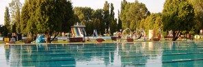 A swimming pool with multiple lanes, surrounded by trees and outdoor seating areas. - Hotel Aqua (Komarom)