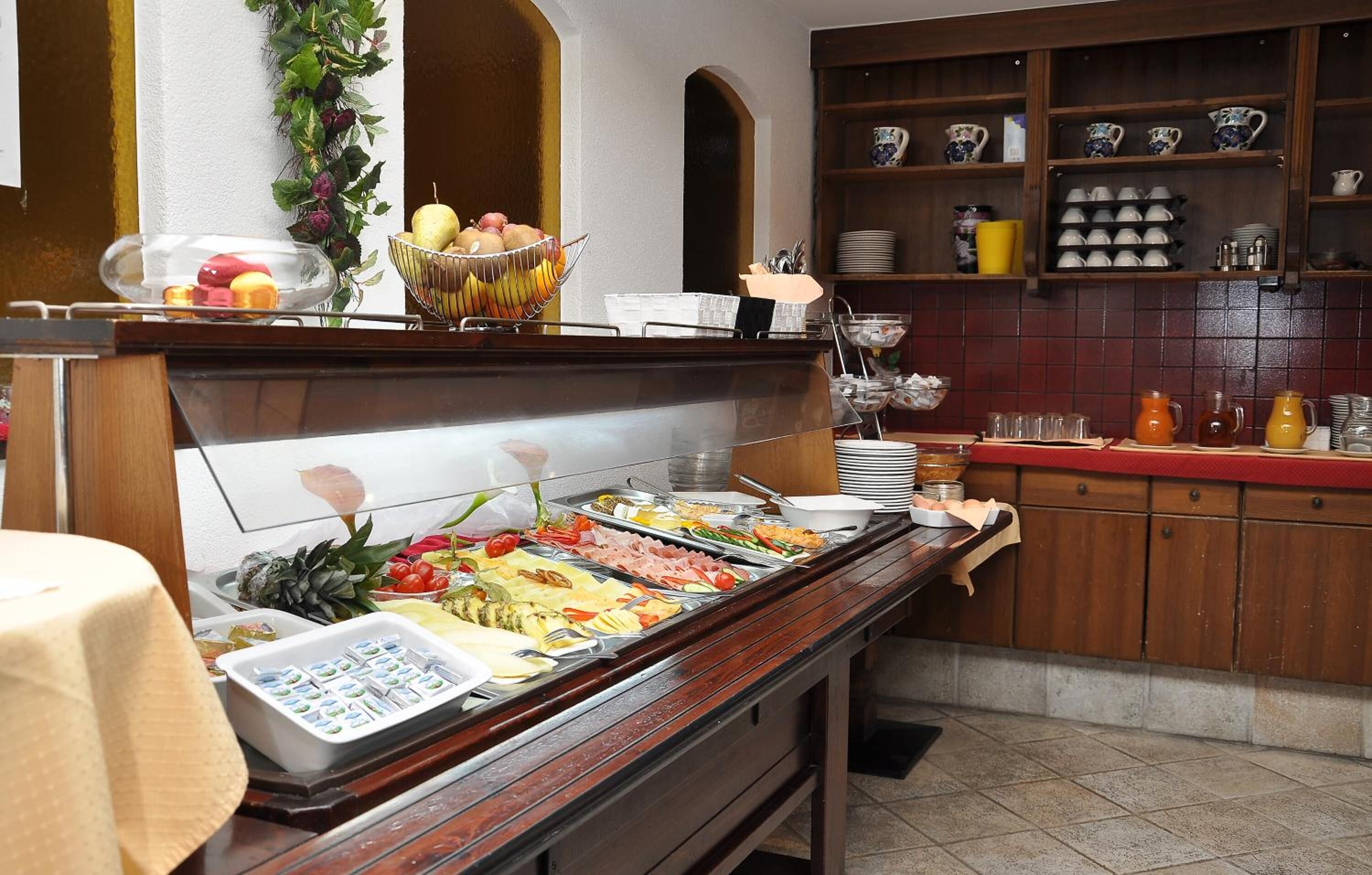 Un'area buffet con diverse opzioni di cibo e una cucina con scaffali pieni di stoviglie e utensili.