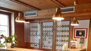 A wooden reception desk with the name "TORWIRT" carved into it. There are three pendant lights hanging above the desk. - Hotel Torwirt (Wolfsberg)