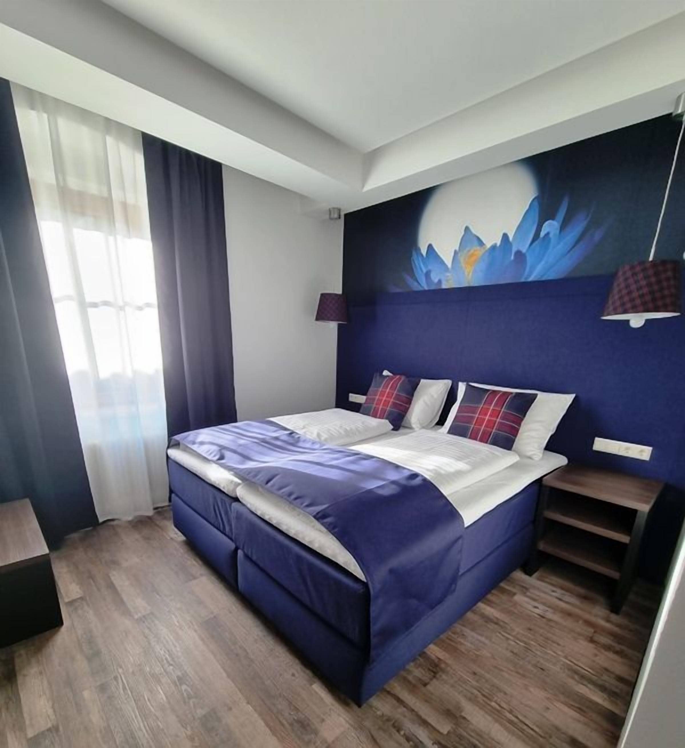 Ein Schlafzimmer mit einem Bett, einem Nachttisch, einer Lampe und einer Wandmalerei.