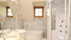 A bathroom with a large bathtub, a walk-in shower, and a double vanity with a mirror. - Hotel Torwirt (Wolfsberg)