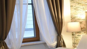 A hotel room with a bed, a window with sheer curtains, a lamp, and a stone wall. - Hotel Torwirt (Wolfsberg)