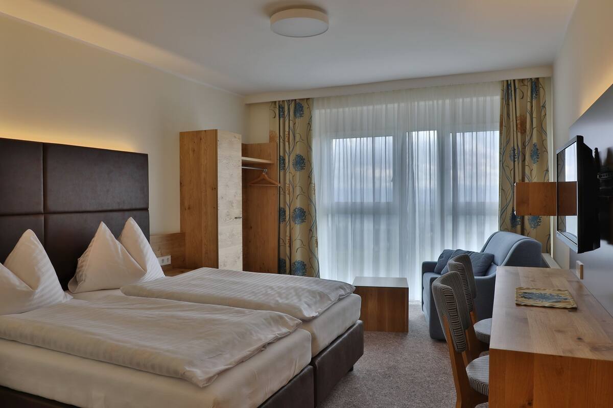 A hotel room with a bed, a desk, a chair, and a wardrobe.