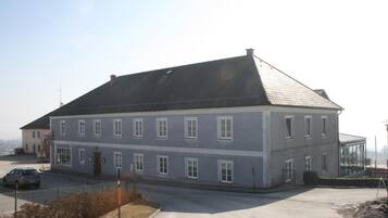 A two-story building with a grey facade, multiple windows, and a sloped roof.