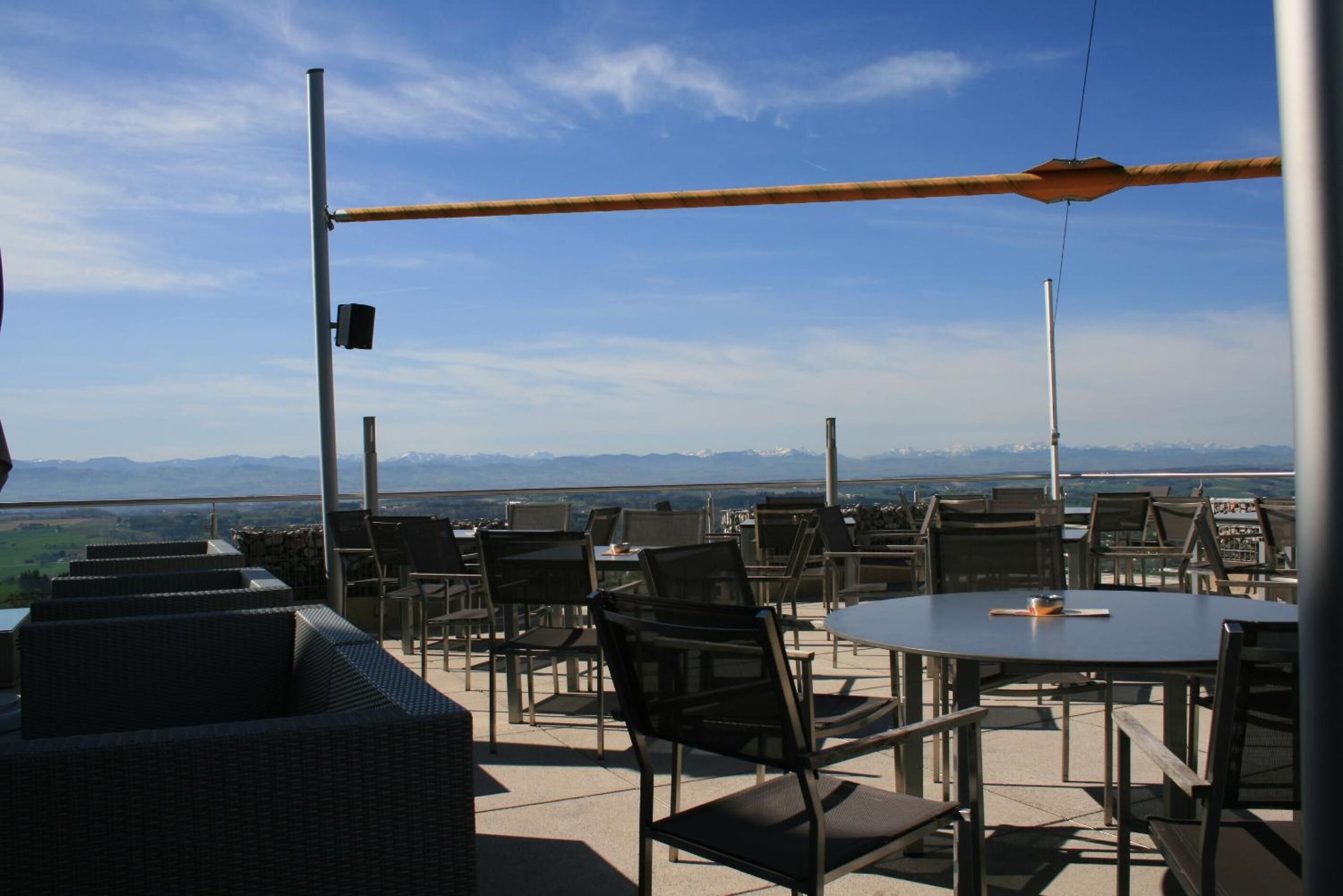 An outdoor seating area with tables and chairs, overlooking a scenic landscape with mountains in the distance.