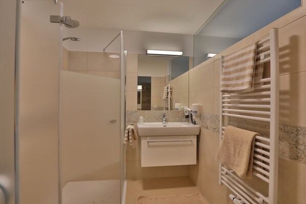 A modern bathroom with a glass shower enclosure, a sink with a towel rack, and a towel warmer. - Gasthof Alpenblick (Ardagger Markt)