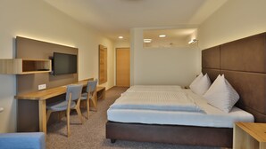 A modern hotel room with a large bed, a desk with a chair, a television, and a small seating area. - Gasthof Alpenblick (Ardagger Markt)