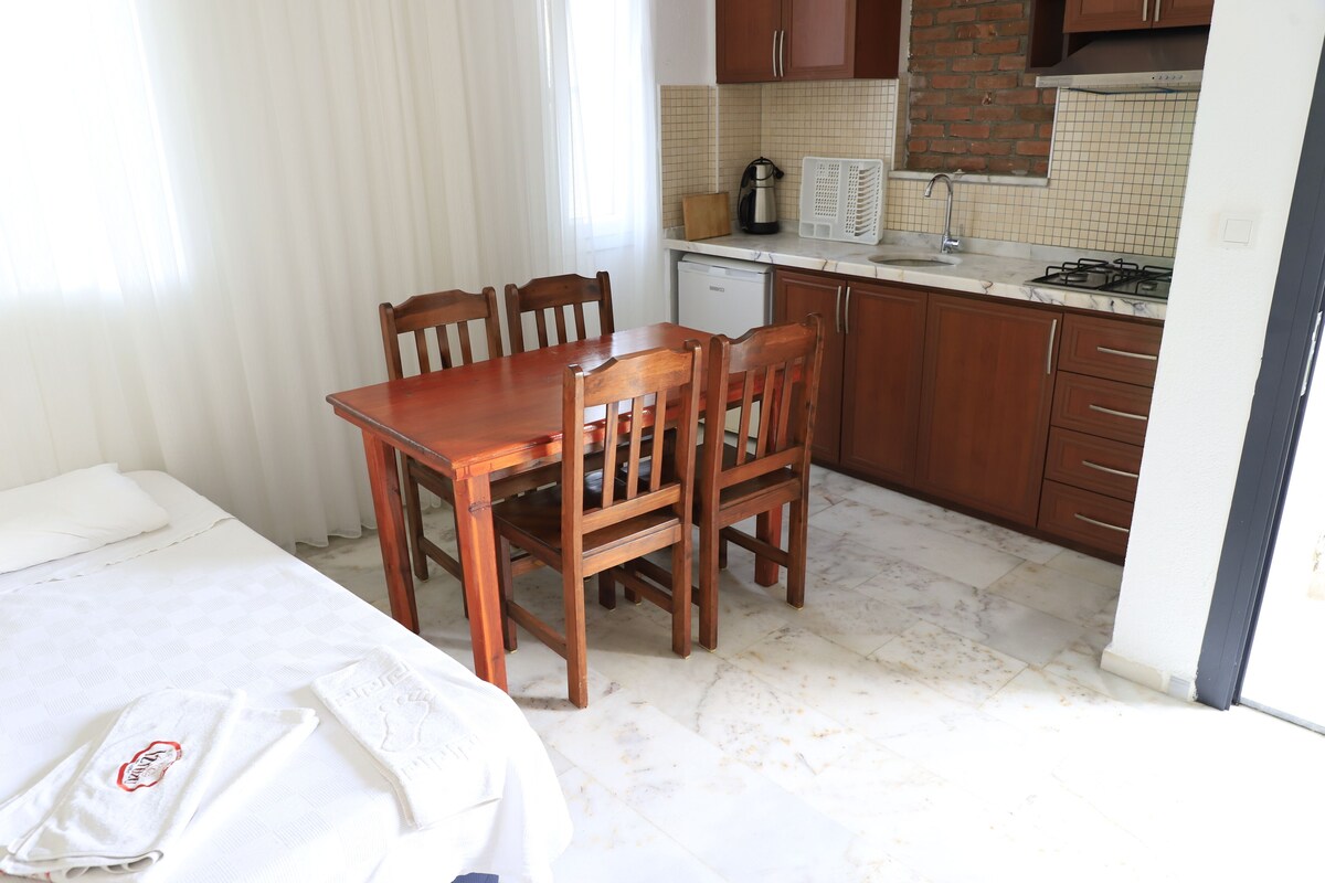 Una cocina compacta con una mesa y sillas, un refrigerador pequeño y una estufa.