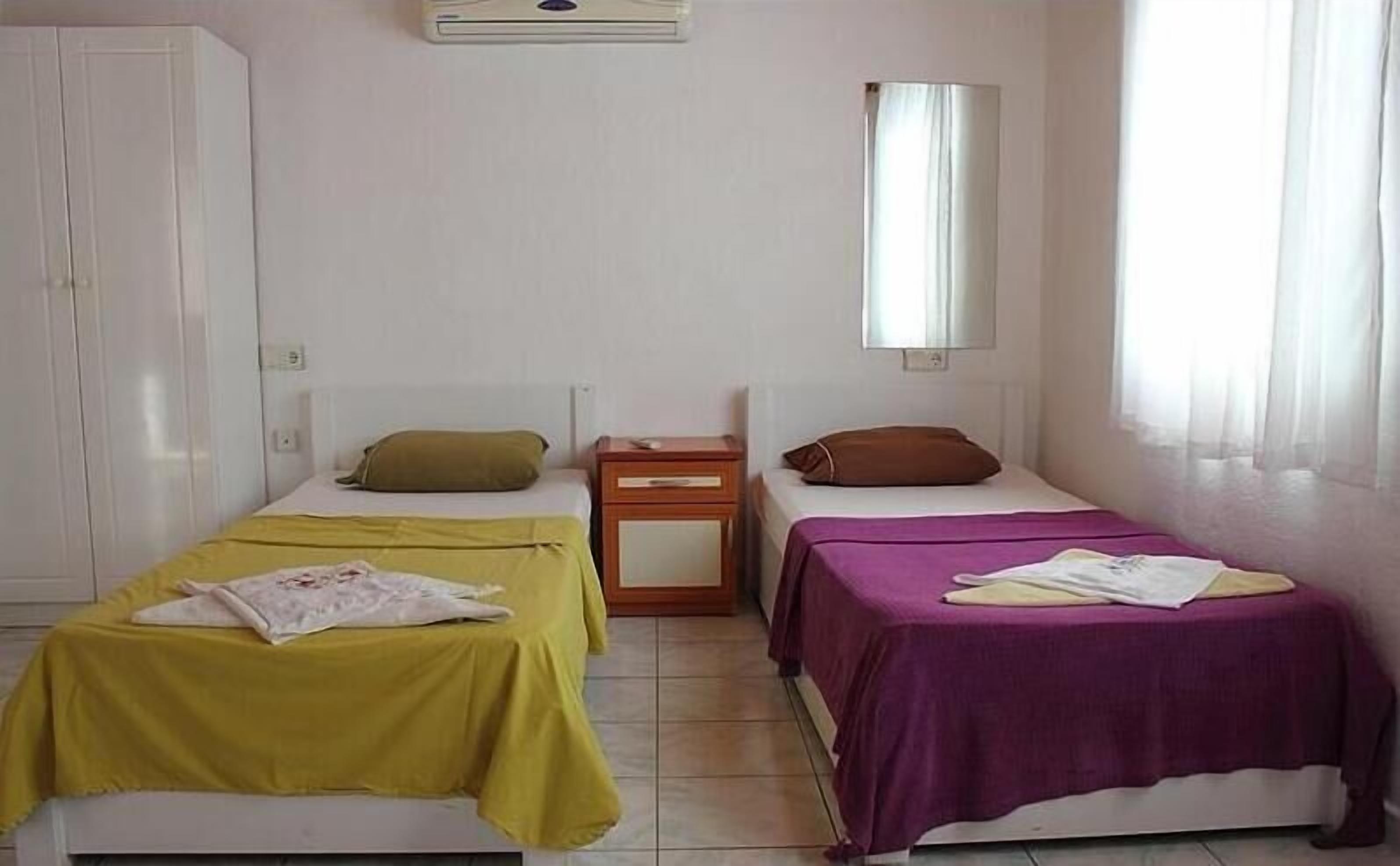 A room with two beds, a wardrobe, a nightstand, and a mirror.