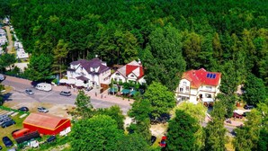 Un hotel con techo rojo, rodeado de bosque denso y una vista despejada del mar.