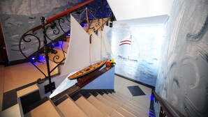 Una escalera con un modelo de velero, una barandilla decorativa y una pared con textura.