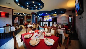 Un restaurante con varias mesas, luces en el techo y una zona de bar.