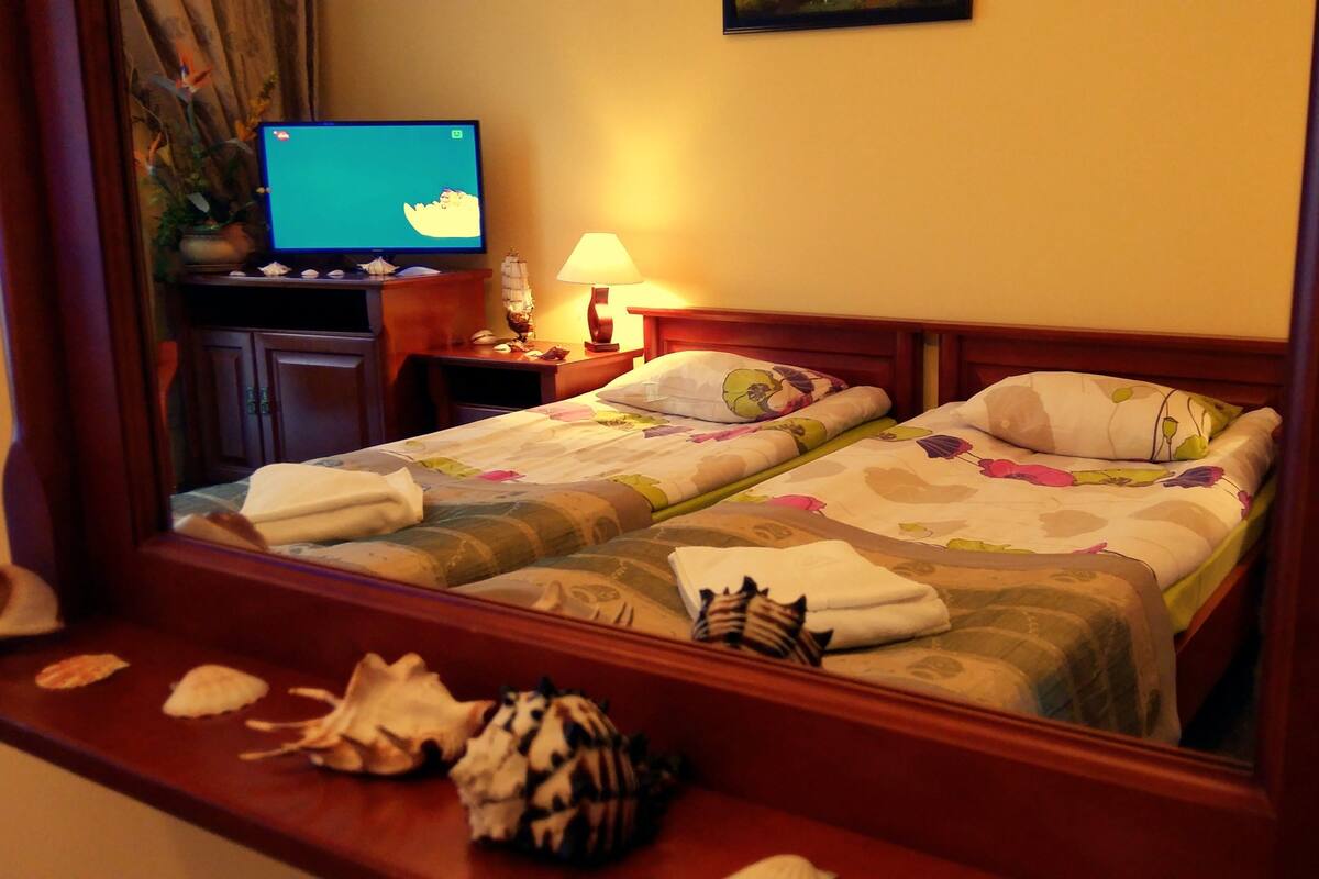 A hotel room with a bed, a television, a lamp, and a decorative item on the nightstand.