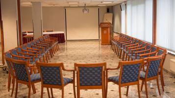 Un salón de conferencias con filas de sillas de madera y un atril con la etiqueta 'Hotel Silver'.