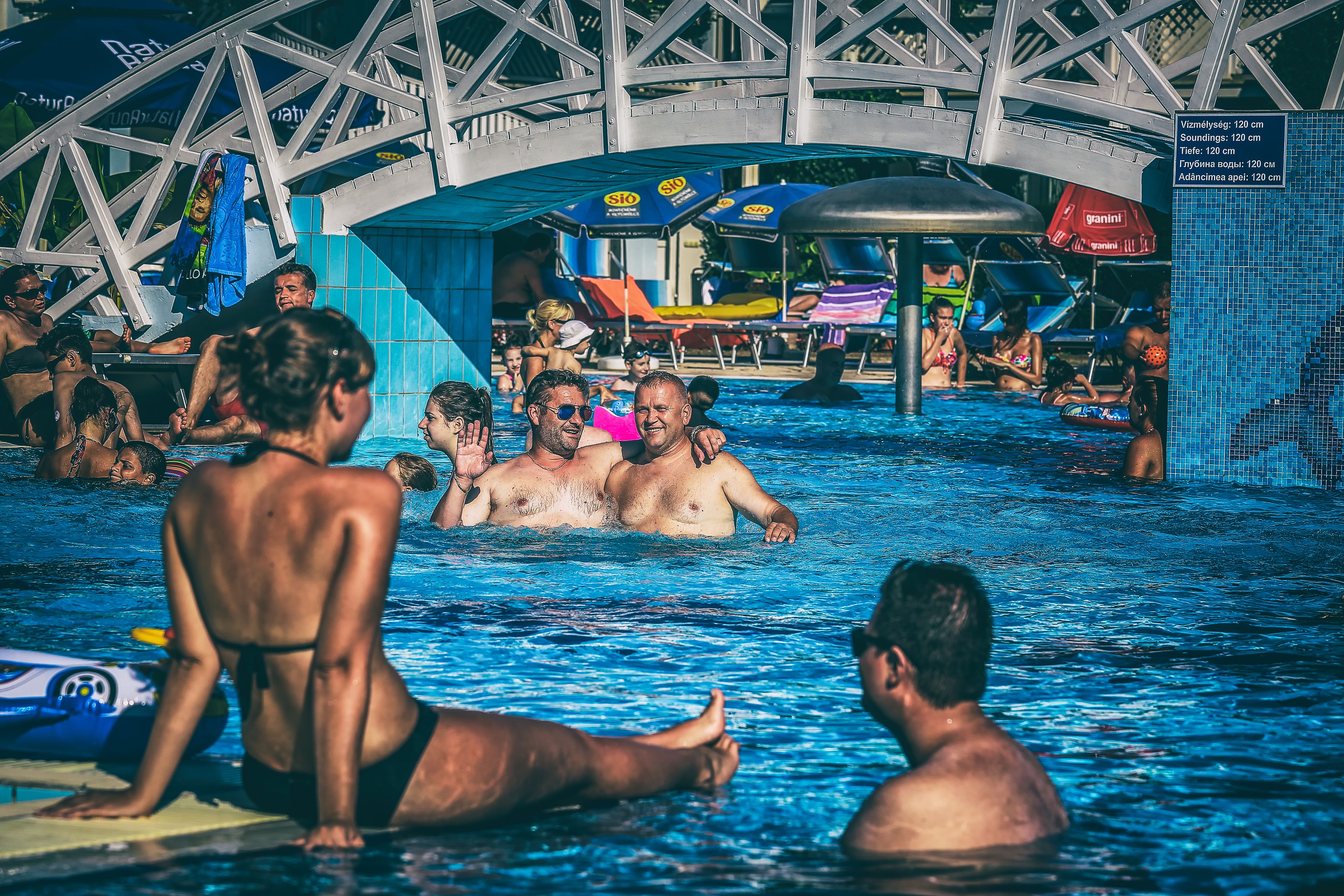 Un espace piscine doté d’une grande structure métallique au-dessus, de chaises longues et de parasols.