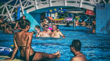 Un espace piscine doté d’une grande structure métallique au-dessus, de chaises longues et de parasols.