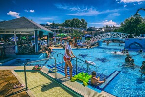A swimming pool area with a lifeguard stand, lounge chairs, and a children's play area. - Hotel Silver (Hajduszoboszlo)
