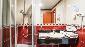 Une salle de bain avec une douche à parois de verre, un lavabo avec un miroir et un téléphone.