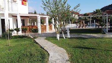 Um hotel com área de estar coberta ao ar livre, piscina e caminho de pedra.