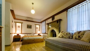 A cozy bedroom with a bed, a sofa, a fireplace, and a window with curtains. - Eski Datca Evleri (Datca)