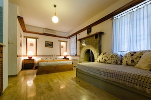 Una camera accogliente con un letto, un divano, un camino e una finestra con tende.