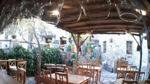An outdoor dining area with wooden tables and chairs, stone walls, and a rustic ambiance. - Eski Datca Evleri (Datca)