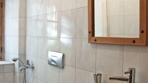 A bathroom with a toilet, a large basin sink, a shower, and a mirror. - Eski Datca Evleri (Datca)