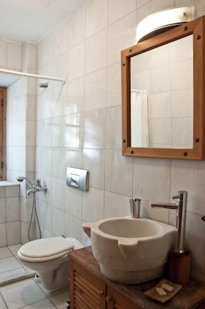 Un bagno con il water, un lavandino capiente, una doccia e uno specchio.