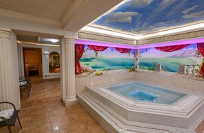 A luxurious bathroom with a large bathtub, a mural of a landscape, and a view of the sea. - Cumulus Hotel (Będzin)