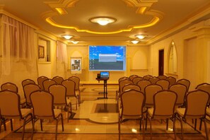 A conference room with rows of chairs facing a projection screen, a podium, and a small table with a laptop. - Cumulus Hotel (Będzin)