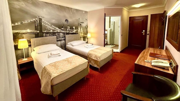 Habitación de hotel con dos camas, un escritorio, un espejo y vistas a la ciudad.
