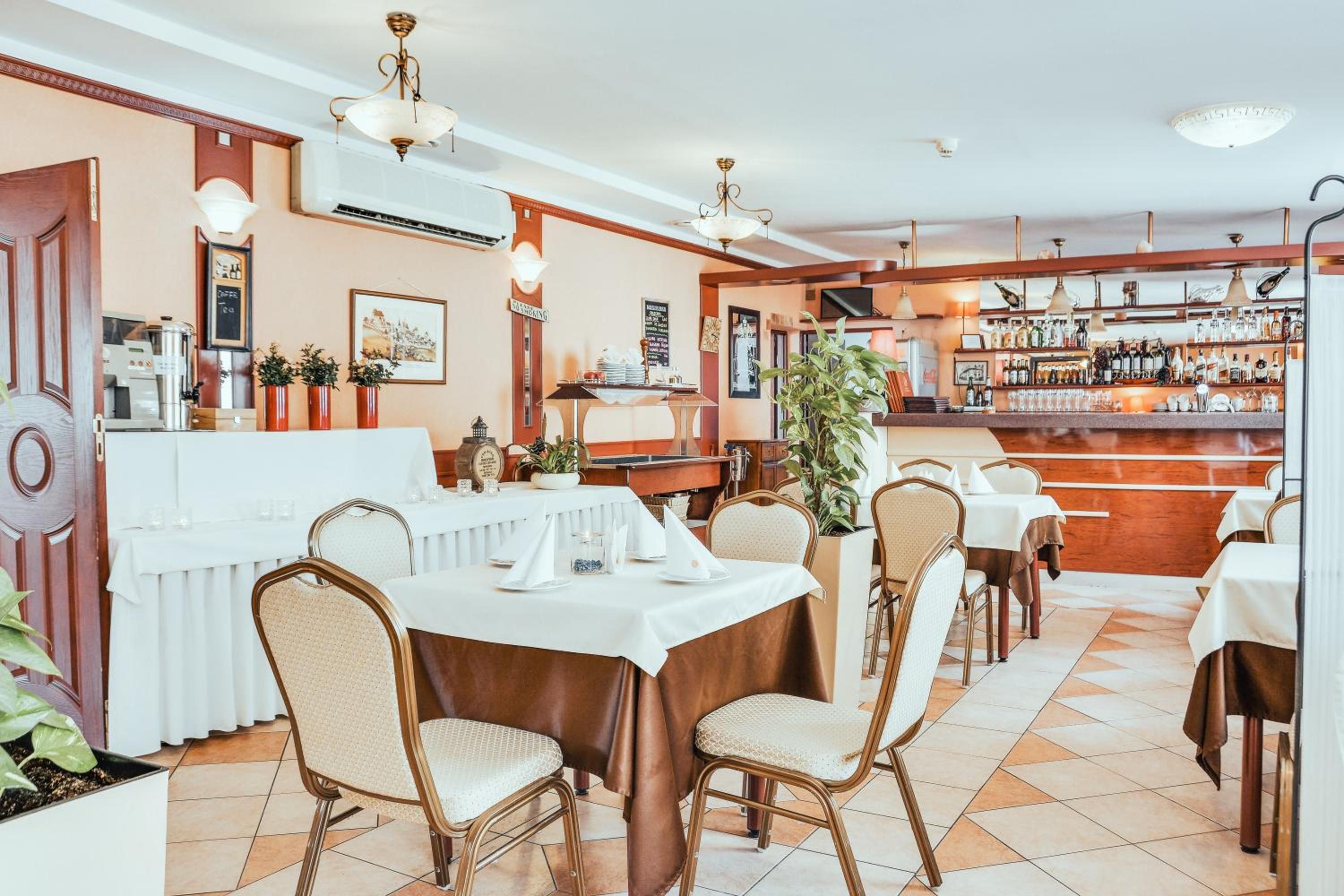 A restaurant with tables and chairs, a bar area with bottles, and a coffee machine.