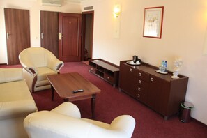 A hotel room with a sofa, armchair, a small table, a cabinet, and a trash bin. - Cumulus Hotel (Będzin)