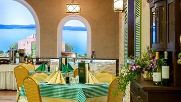 Un comedor con mantel a cuadros, sillas de mimbre y vista al mar.