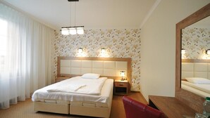 A hotel room with a bed, bedside tables, a mirror, and a desk with a chair. - Dworek Eureka (Czechowice-Dziedzice)