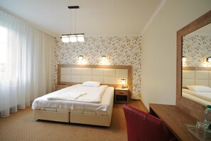 Una habitación de hotel con cama, mesitas de noche, espejo y escritorio con silla.